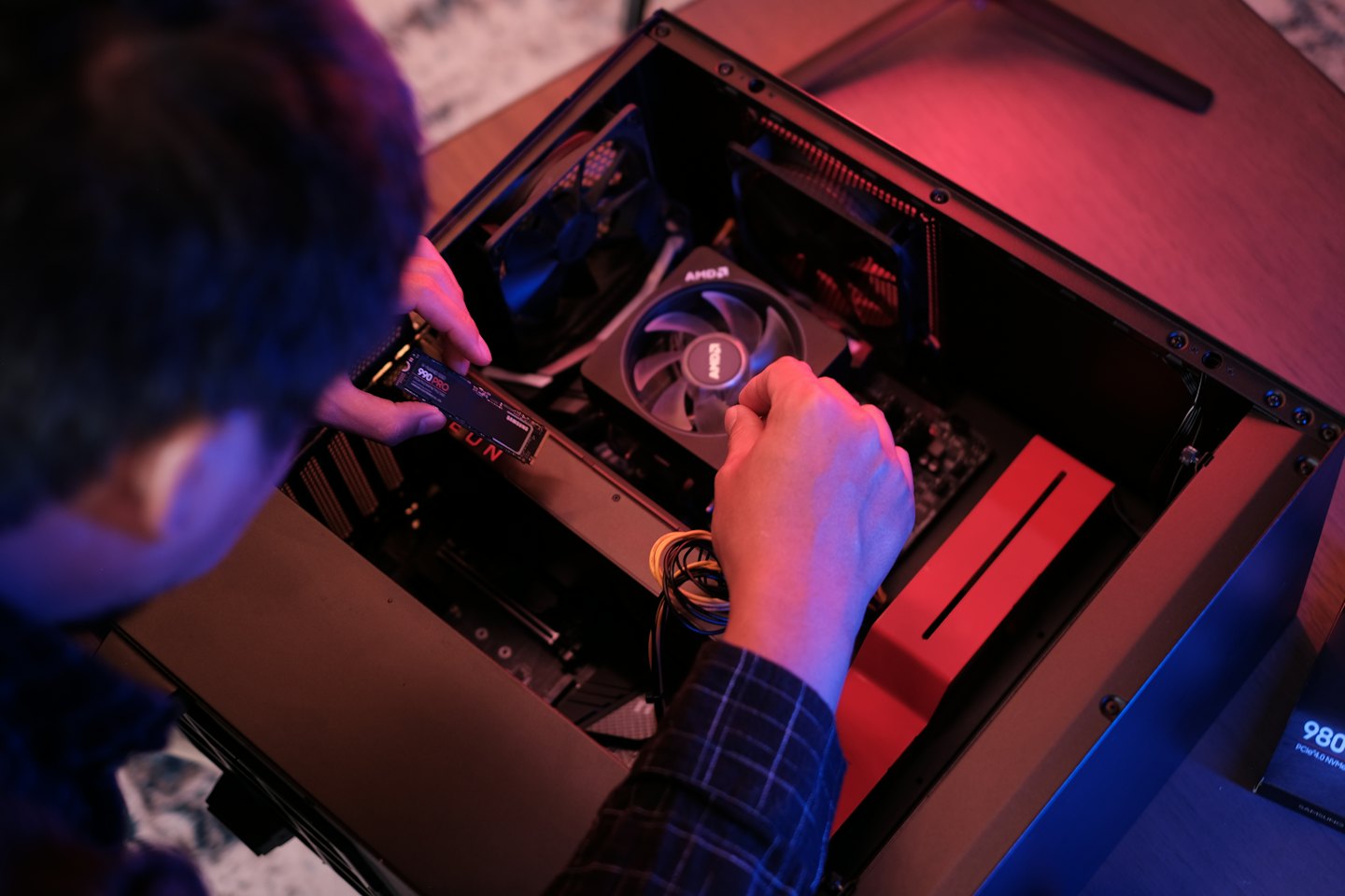 Une personne installe un SSD dans un boîtier d'ordinateur ouvert.